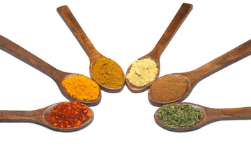 Different kind of spices on a white background.  Oriental spices in spoons, red peppers, curry powder, cinnamon powder, mint powder, colorful peppers. Flat lay, top view.