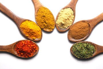 Different kind of spices on a white background.  Oriental spices in spoons, red peppers, curry powder, cinnamon powder, mint powder, colorful peppers. Flat lay, top view.