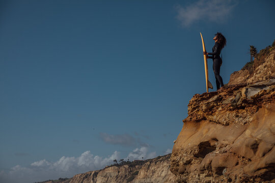 Black Woman carrying a surfboard