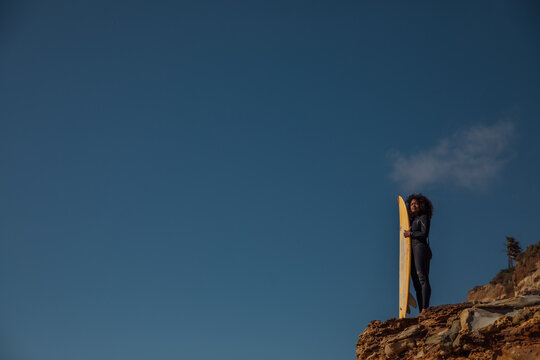 Black Woman carrying a surfboard