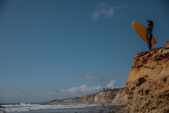Black Woman carrying a surfboard