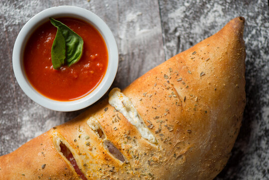 Calzone with marinara sauce over a wood with flour