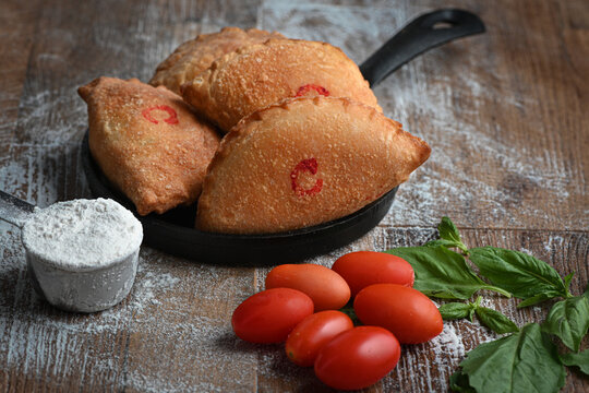 Panzerotti over a black pan in a wood table