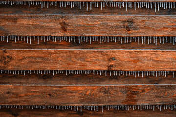 Fototapeta na wymiar The texture of the icy painted boards with many icicles. Natural background.
