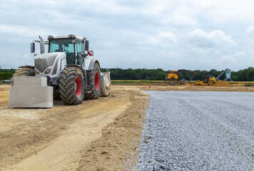Obraz premium Niveleuse de terrassement sur un chantier avec route et gravillons