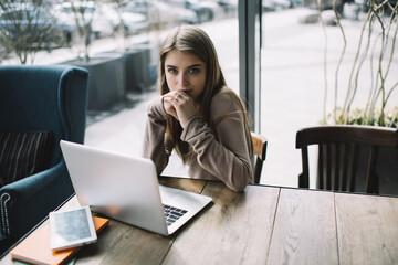 Thoughtful woman with laptop in comfortable workplace