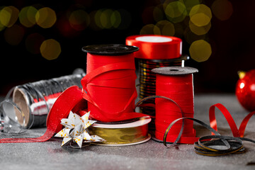 Fototapeta na wymiar Christmas different ribbon spools for decorating gifts on a dark background with bokeh