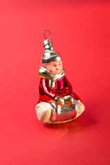 Old soviet decoration for the Christmas tree, glass toy little girl close up on red background