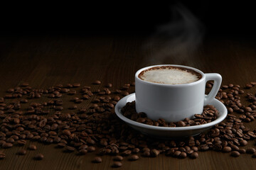 A cup of hot cappuccino on a saucer and scattered coffee beans