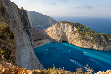 High angle panorama on the shipwreck ship thrown onto a sandy beach surrounded by impenetrable clifs and turquoise waters of the Aegean Sea