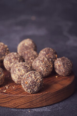 Healthy homemade energy balls on wooden plate. Vegan candies, sweets made of nuts and dates.