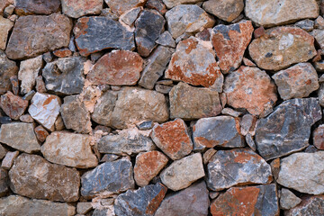 Textured background of stone wall made of natural multicolored stones. Close-up