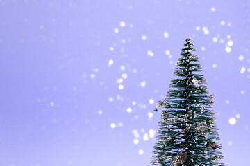Trendy purple Christmas background - Christmas tree or New Year tree with decorations and bokeh lights on trendy lilac background with copy space. Selective focus, color of the year concept