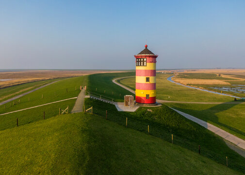 The striped red and yellow Pilsum lighthouse on the shores of the Wadden Sea in Germany