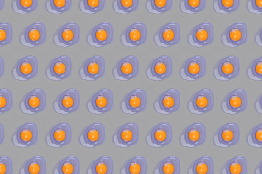Color of the year 2022 and 2021 concept. Pattern made with egg yolks, fresh organic chicken egg in trendy lilac color on gray background, selective focus. World egg day.