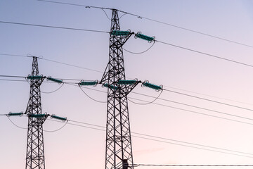 View of two electricity pylons against clear sky at dusk in winter