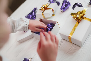 Obraz premium Trendy Color of Year. 2022. child's hands collect vintage toys Very peri color in gift wrapping. Packing gifts for New Year and Christmas.