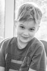 Black and white portrait of a cute boy, the child smiles, joy on the child's face.