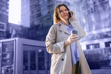 A business woman is talking on the phone in front of a business center. Toned in trendy Very Peri color of the Year 2022