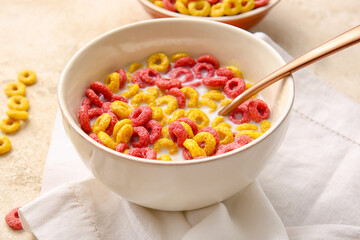 Bowl of colorful cereal rings on light grunge background