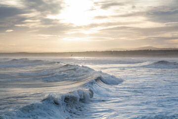 Fototapeta premium LOSSIEMOUTH, MORAY, SCOTLAND - 9 DECEMBER 2021: This is a scene at the east beach area of the harbour with waves just after sunrise at Lossiemouth, Moray, Scotland on 9 December 2021.