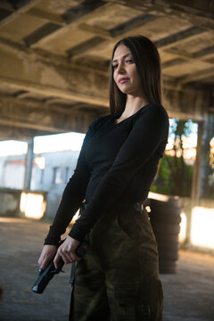 A girl with an air soft gun in a black tight long-sleeved T-shirt