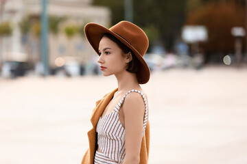 Fototapeta Young fashionable woman in felt hat on city street obraz