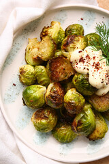 Plate with delicious roasted Brussels cabbage and sauce on table, closeup