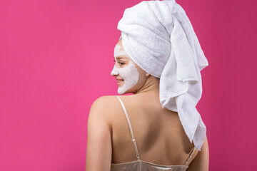 Fototapeta premium Girl with a cosmetic mask on her face in a white towel.