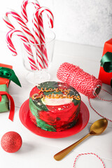 Plate with tasty bento cake and Christmas decor on light wooden table