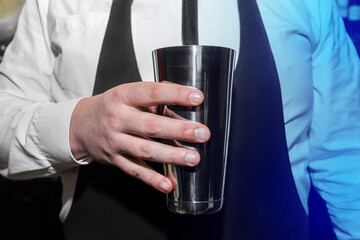 The hand of a professional bartender man holds a tool for mixing and making shaker cocktails