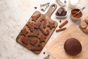Wooden board with tasty chocolate Christmas cookies and dough on light background