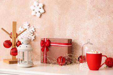 Christmas gift, lantern and decor on table near color wall