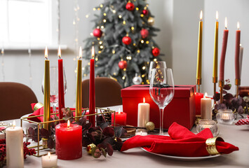 Dining table with candles and beautiful setting for Christmas celebration in room