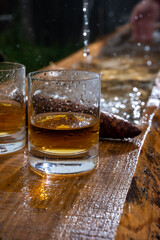 Glasses of strong scotch single malt whisky and rain water drops