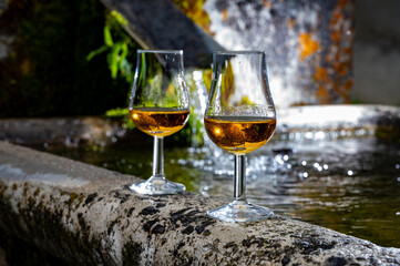 Glasses of strong scotch single malt whisky served on old stone reservoir for water from mountain spring