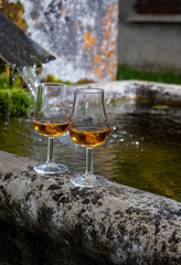 Glasses of strong scotch single malt whisky served on old stone reservoir for water from mountain spring