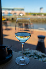 Glass of white wine served in cafe with view on harbour of Harlingen, vacation in Friesland, Netherlands