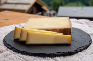 Cheese collection, French cow cheese comte, beaufort, abondance and french mountains village in Haute-Savoie on background