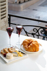 Drinking of Kir Royal,  French aperitif cocktail made  from creme de cassis topped with champagne, typically served in flute glass, with view on old French village