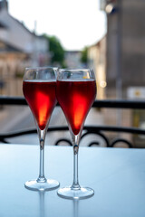 Drinking of Kir Royal,  French aperitif cocktail made  from creme de cassis topped with champagne, typically served in flute glass, with view on old French village