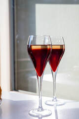 Drinking of Kir Royal,  French aperitif cocktail made  from creme de cassis topped with champagne, typically served in flute glass, with view on old French village