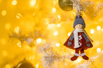Close up of doll toy and garlands on white yellow Christmas tree