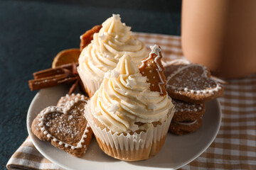 Plate with delicious Christmas cupcakes and cookies on black background