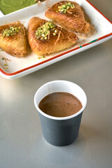 Turkish Coffee with sweets, kunafa, with pistachio nuts on top on gray background