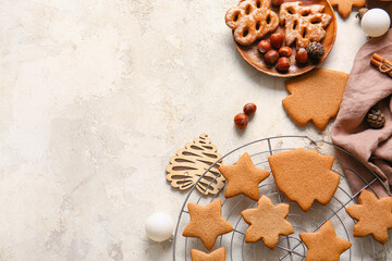 Plate and grid with sweet Christmas gingerbread cookies on light background