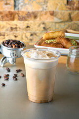 Iced Latte coffee with Arabic sweets and coffee beans on dark gray background