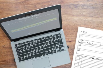パソコンモニターに映る中部地方の有効求人倍率と履歴書