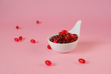Krill oil capsules in a spoon on a light pink background.Natural supplements and vitamin.omega fatty acids.Healthy eating and food supplements 
