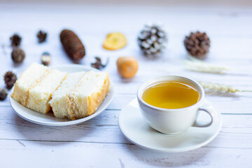 Cake and yellow tea on a white wooden table in the morning